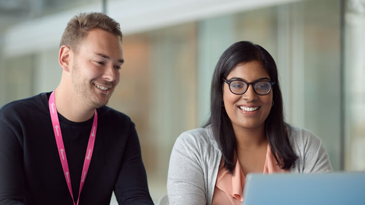 Experian employee sat in an open plan office looking down at her laptop smiling