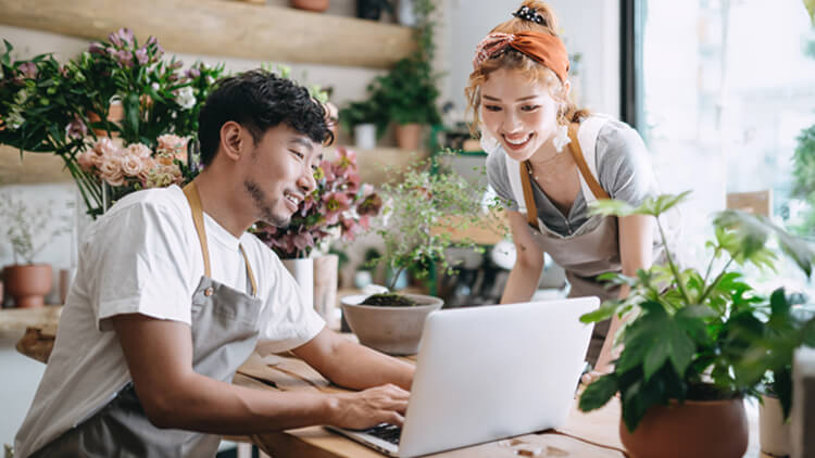 Male and female florest business owners sat around a laptop